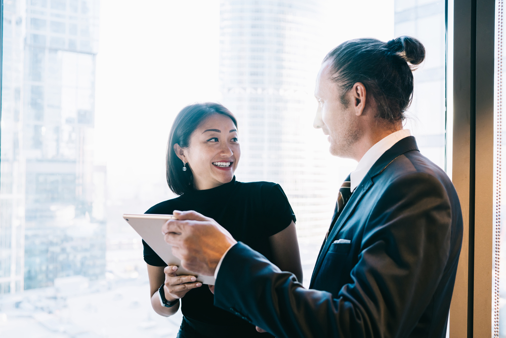 Two people holding an iPad and smiling at each other