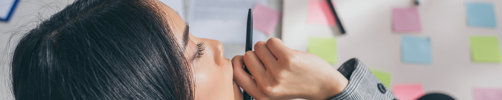 One person holding a pen near their mouth and thinking